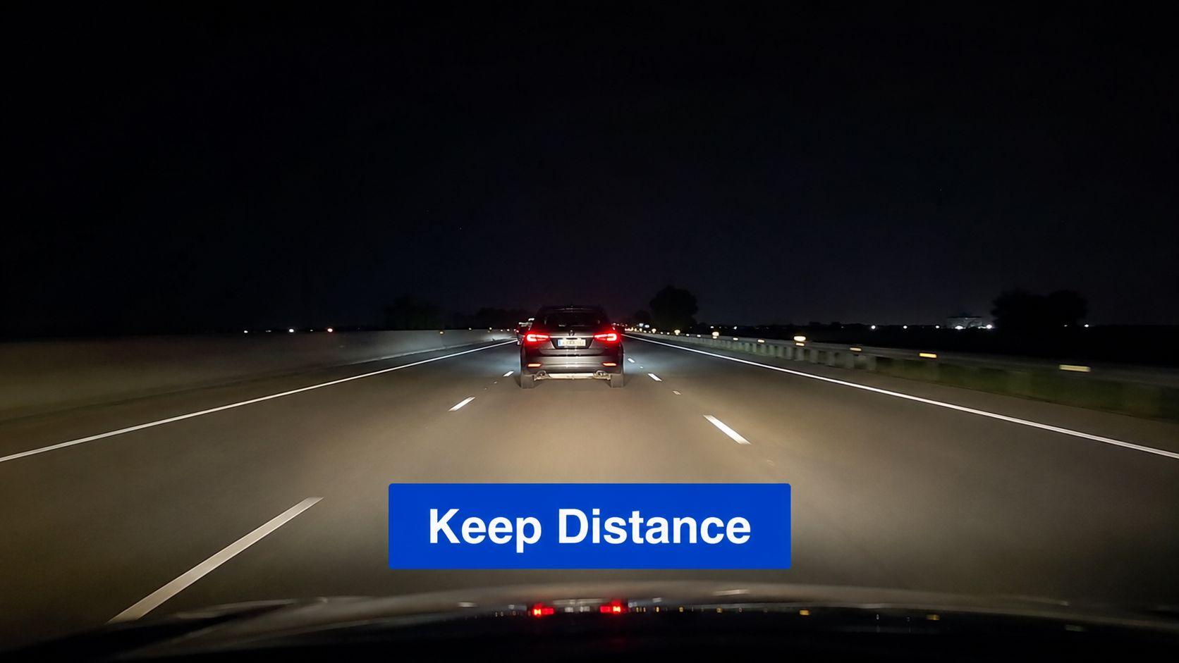 A view from inside a car driving on a highway at night behind another vehicle.