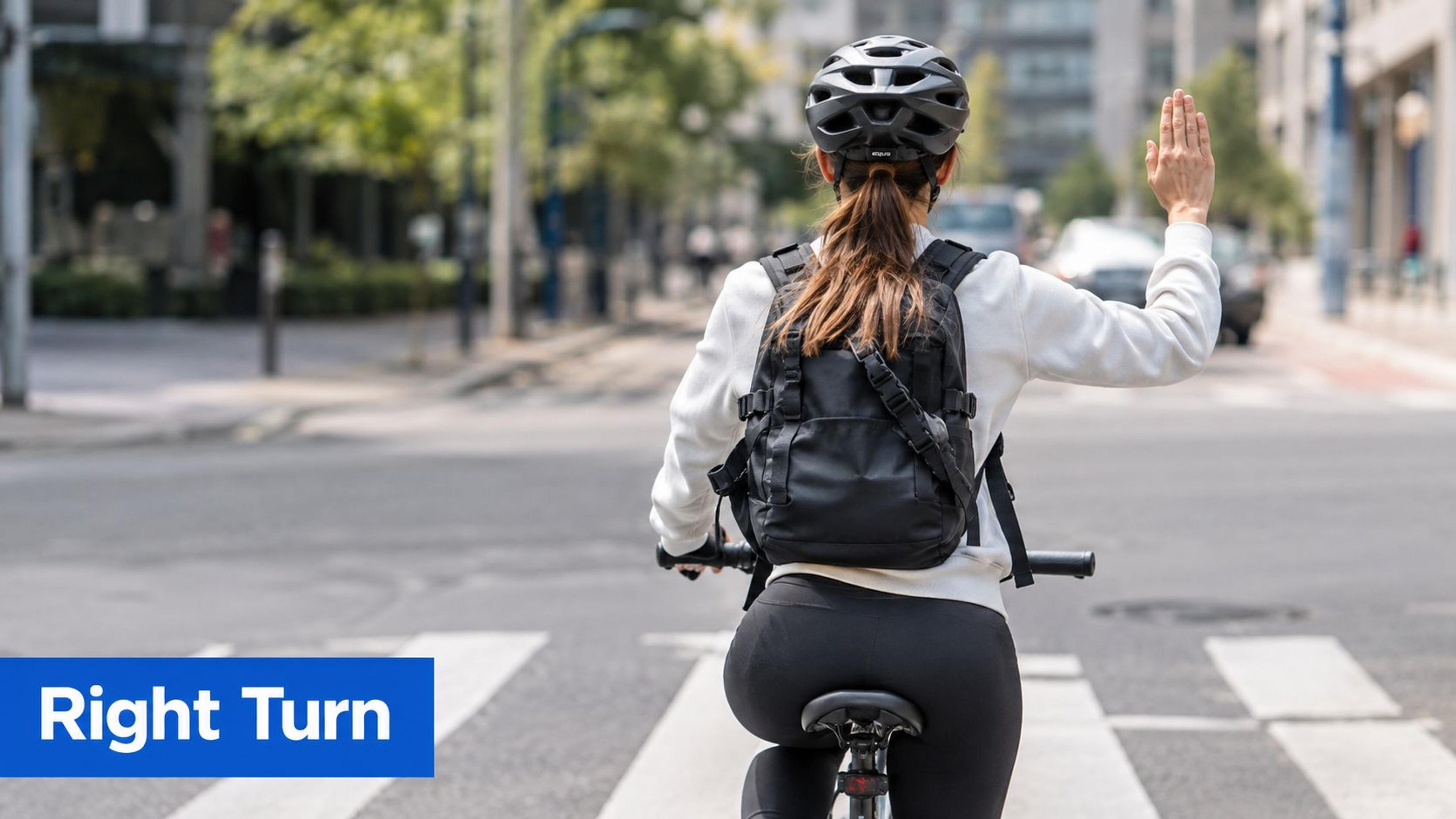 A cyclist on a road demonstrates the correct hand signal for turning right by extending their right arm.