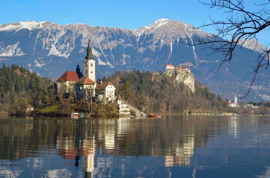 Bled Island's church reflects in the lake below Bled Castle