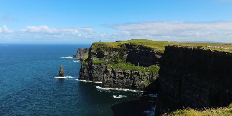 Grass-topped Cliffs of Moher rise above blue Atlantic water