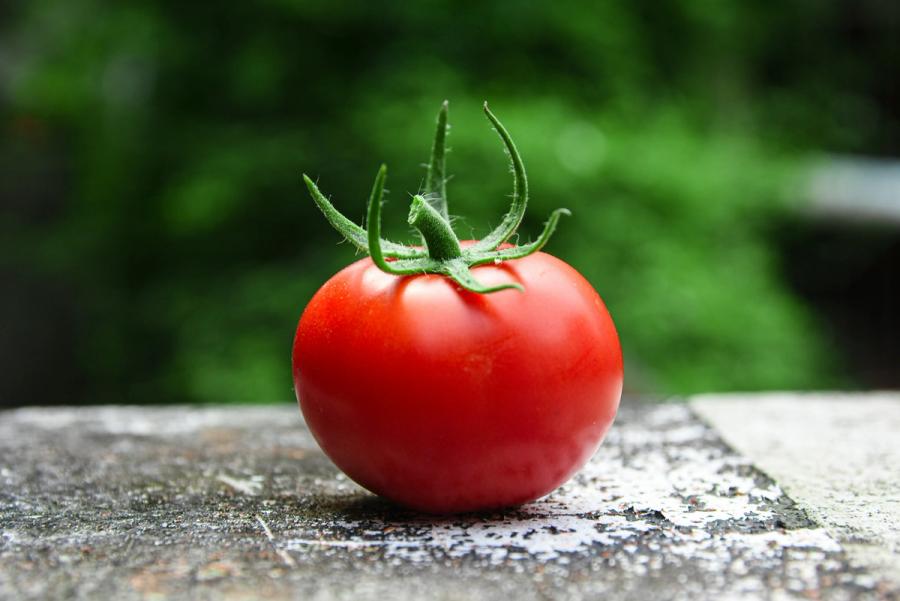 A ripe red tomato resting on a stone surface