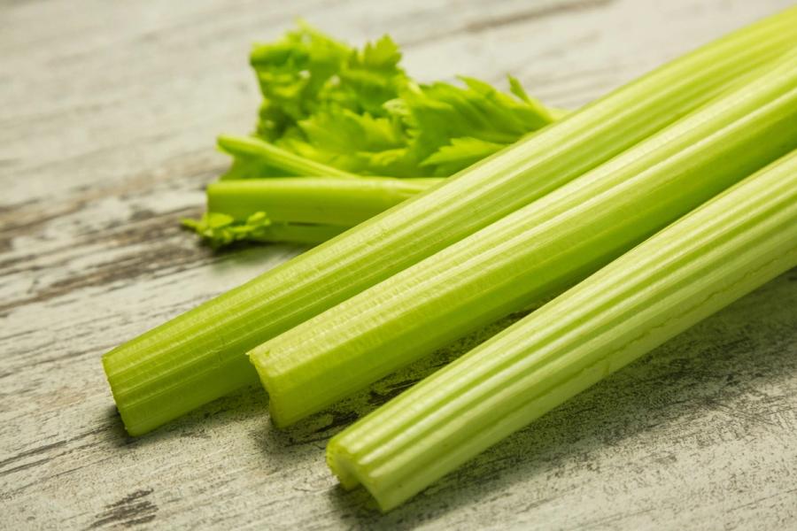 Fresh celery stalks and leaves on a wooden surface