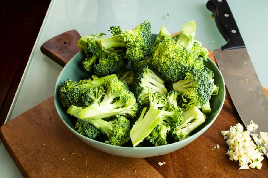 Raw broccoli florets in a bowl on a cutting board