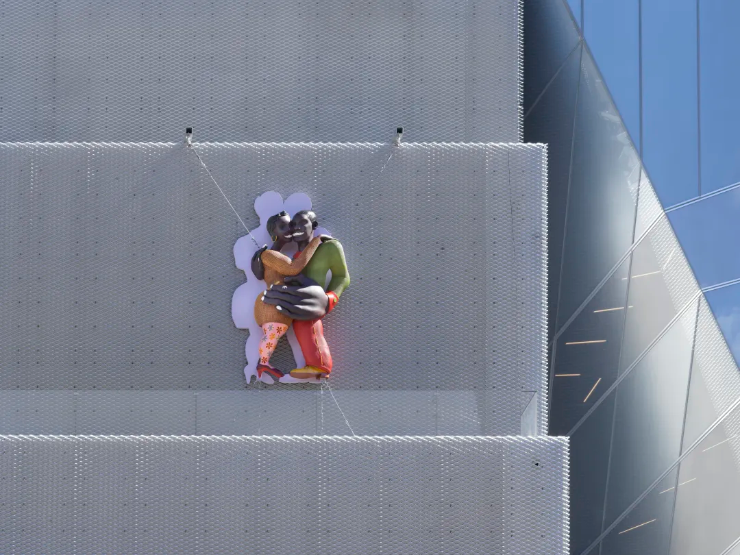 Tschabalala Self’s new commission for the museum, Art Lovers, climbs the exterior wall. Two enormous, gleaming bodies embrace, marking the “kissing point” between the SANAA building and OMA’s new addition.
