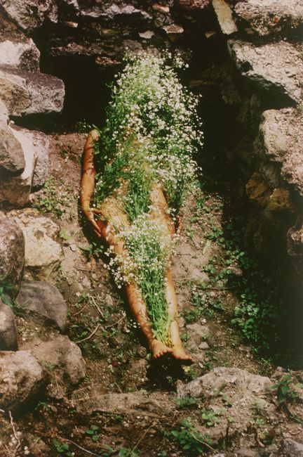 Mendieta lies in an ancient tomb with white flowers covering her body