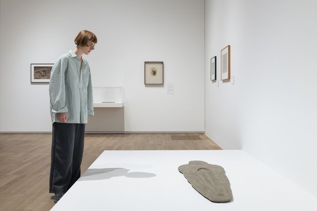 A visitor looks at a sculpture with a female form on a display surface