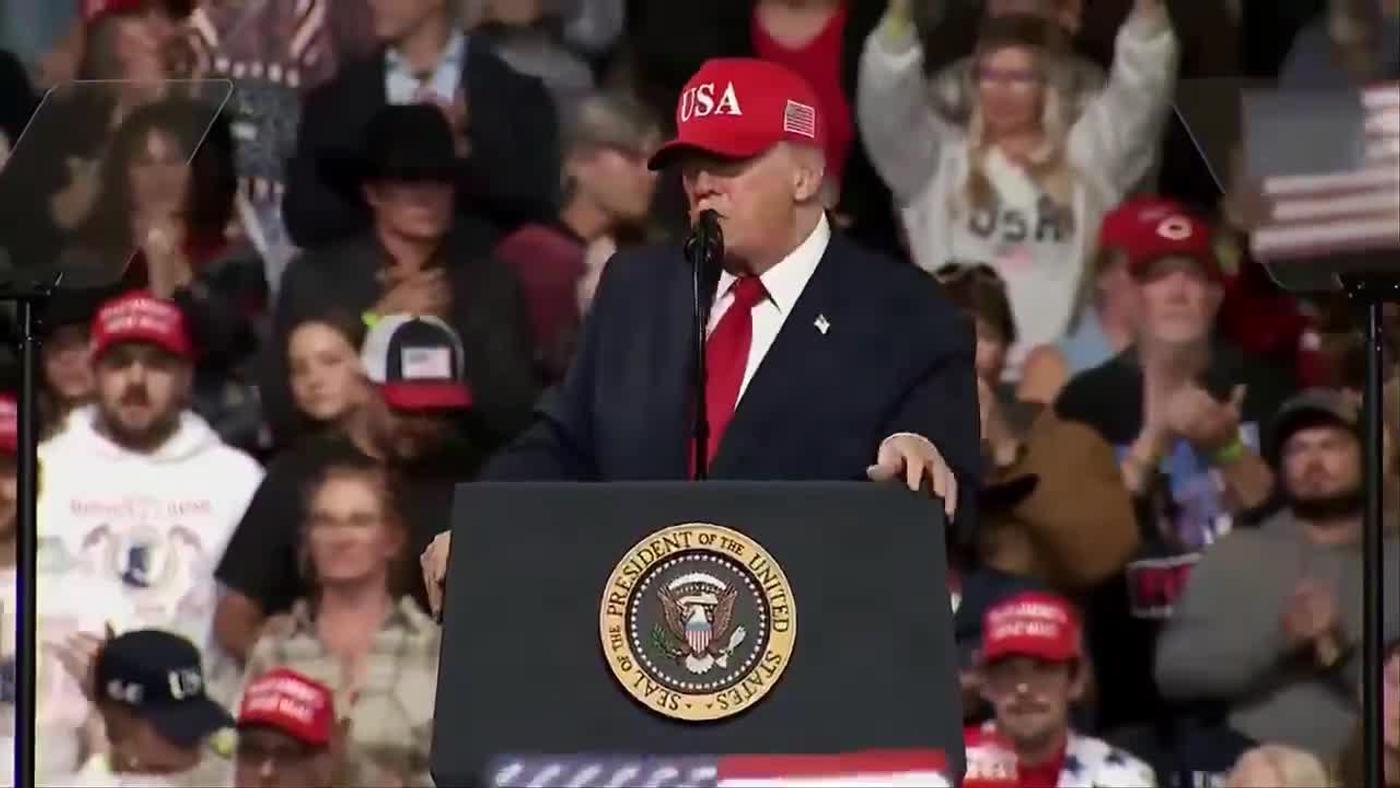 President Donald J. Trump, in front of a crowd that includes cowboy hats and American flags, speaks at a lectern bearing the presidential seal at his rally in Montana, October 14, 2026 (still from Rapid Response 47 video)