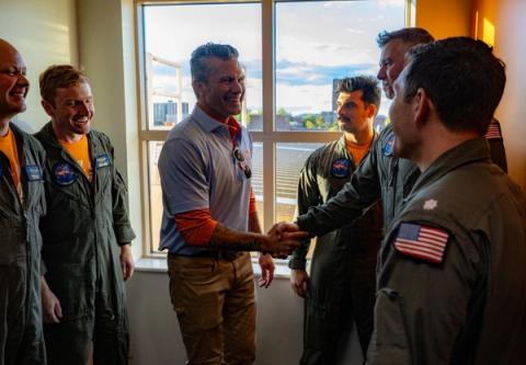 Stand-in photo (Oct. 17, 2026): A man in a gray polo over an orange shirt smiles and shakes hands with aircrew members in flight suits beside a window in Tennessee. Secretary of War Pete Hegseth on X, Oct. 17, 2026: “For generations, the Volunteer State has raised its right hand and said, “SEND ME.””