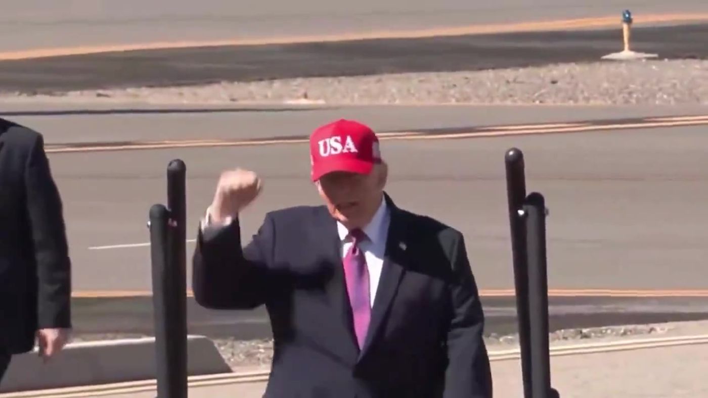 President Trump, in a red USA cap, pumps his fist on the tarmac in Bullhead City, Arizona, October 14, 2026 (still from Rapid Response 47 video)