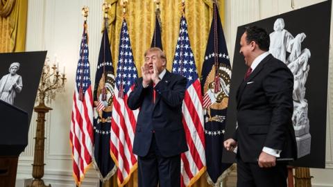 President Trump at the White House Columbus Day celebration with Christopher Columbus statue posters and presidential flags, October 2026 (Official White House photo)