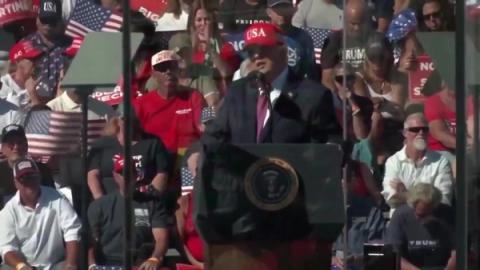 President Trump, in a red USA cap, speaks at a podium bearing the presidential seal before a crowd at his rally in Bullhead City, Arizona, October 14, 2026 (still from Rapid Response 47 video)