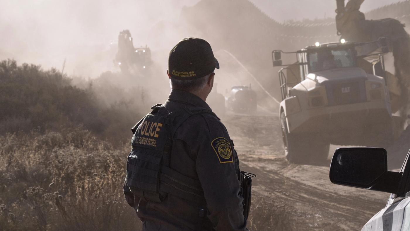 A U.S. Border Patrol agent stands watch as border wall construction crews work in the distance near Tecate, Calif., June 26, 2026. New infrastructure and advanced technology serve as force multipliers for agents overseeing these remote areas. CBP photo by Jeff Underwood (U.S. Customs and Border Protection photo)