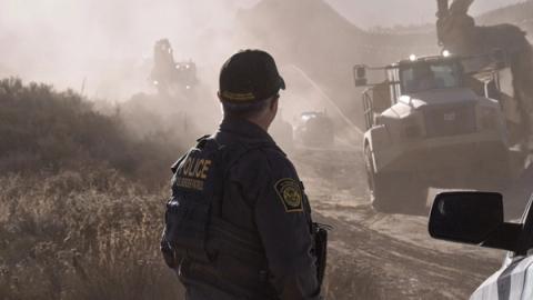 A U.S. Border Patrol agent stands watch as border wall construction crews work in the distance near Tecate, Calif., June 26, 2026. New infrastructure and advanced technology serve as force multipliers for agents overseeing these remote areas. CBP photo by Jeff Underwood (U.S. Customs and Border Protection photo)