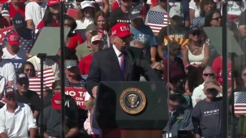 President Trump speaks at a podium bearing the presidential seal before a packed crowd at his rally in Bullhead City, Arizona, October 14, 2026 (still from Rapid Response 47 video)