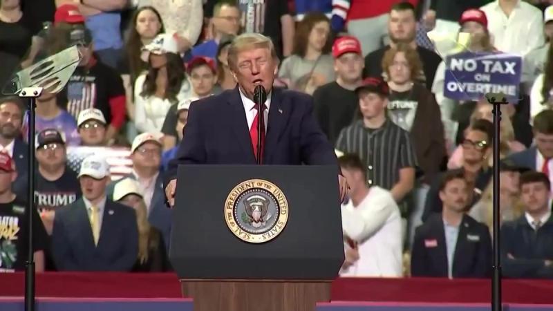 President Trump at the Youngstown rally podium with a NO TAX ON OVERTIME sign visible, October 12, 2026 (still from Rapid Response 47 video)