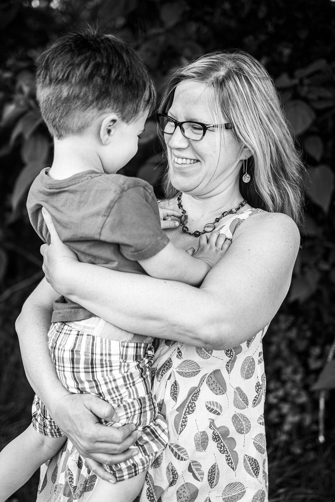 Smiling woman holds young boy in loving embrace.