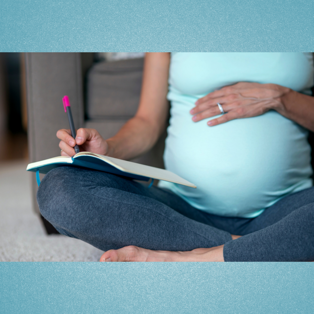 Pregnant woman journaling while seated on couch.