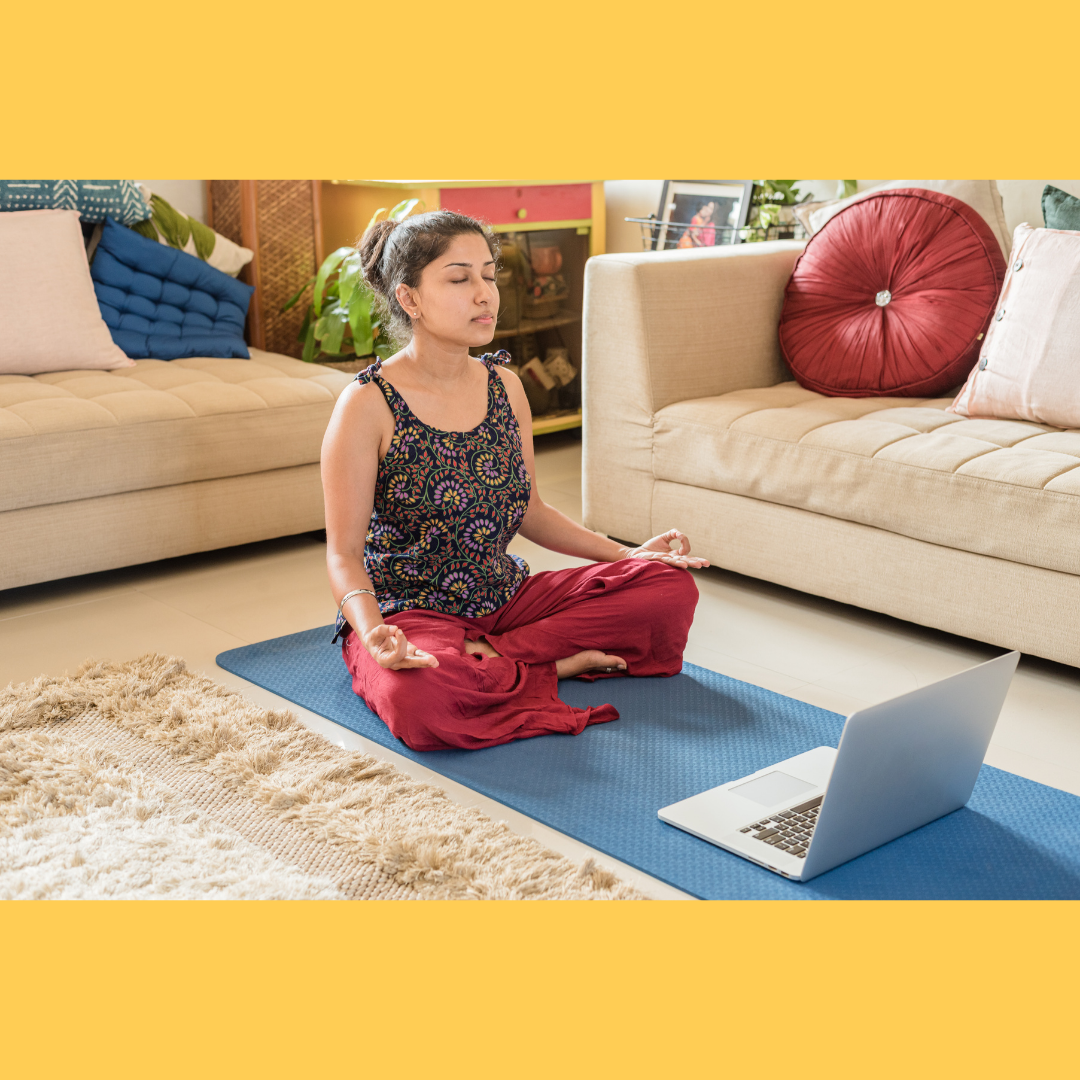 Woman meditating at home with laptop.