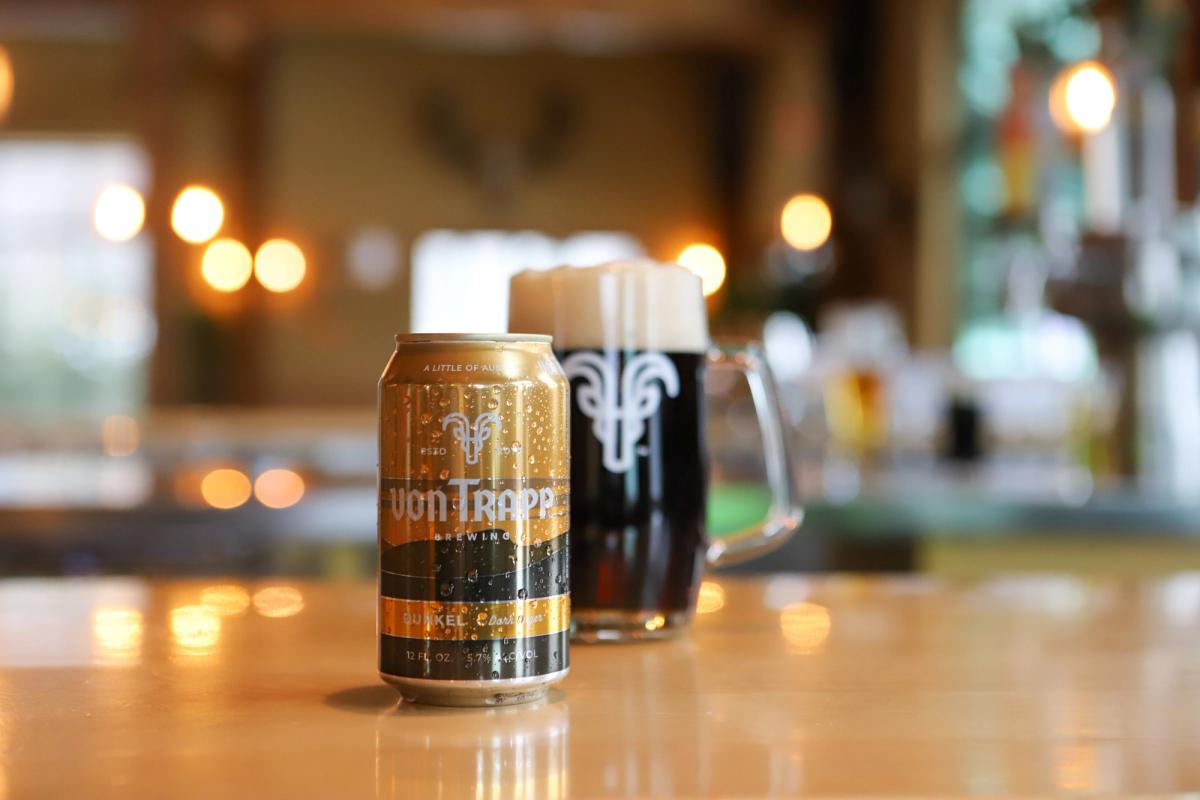 A von Trapp Dunkel can beside a mug of dark lager at the bar.