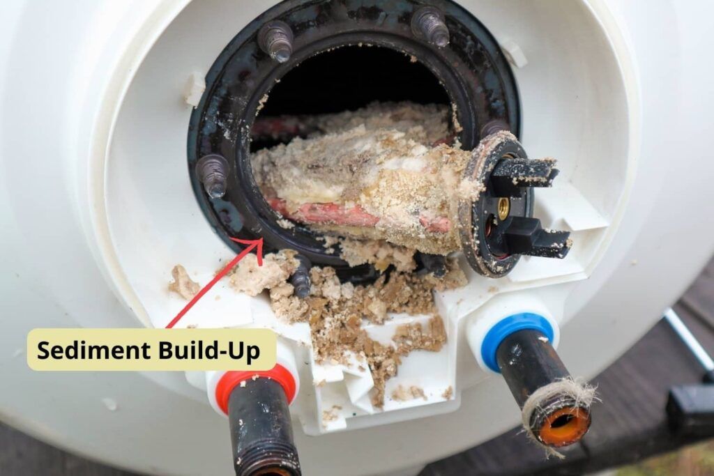 Opened water heater tank with heating element caked in sediment build-up