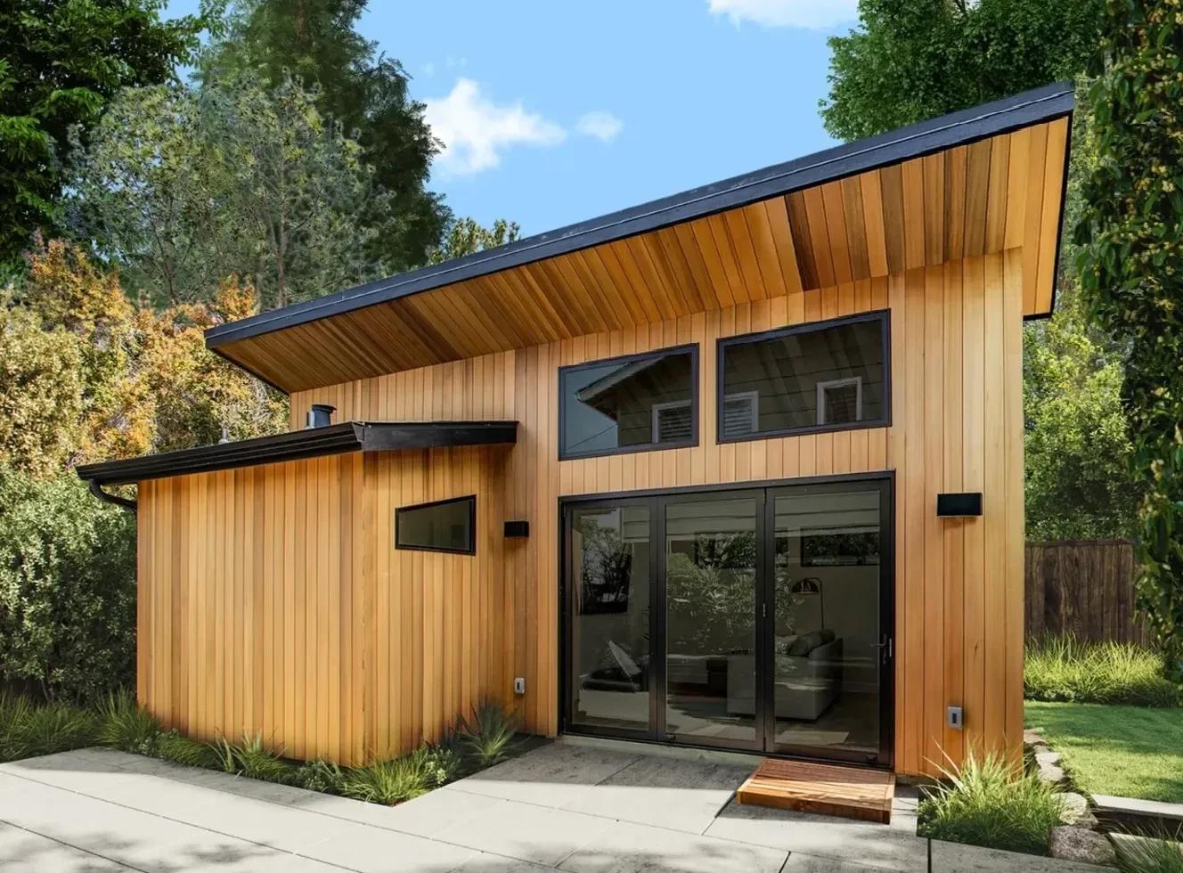 Modern cedar-clad backyard ADU with a slanted roof and large glass sliding doors