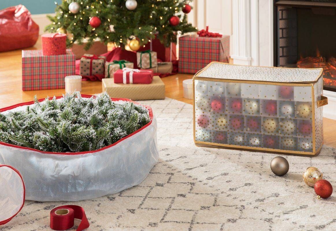 Christmas tree and ornaments being packed into zippered storage bags beside wrapped gifts
