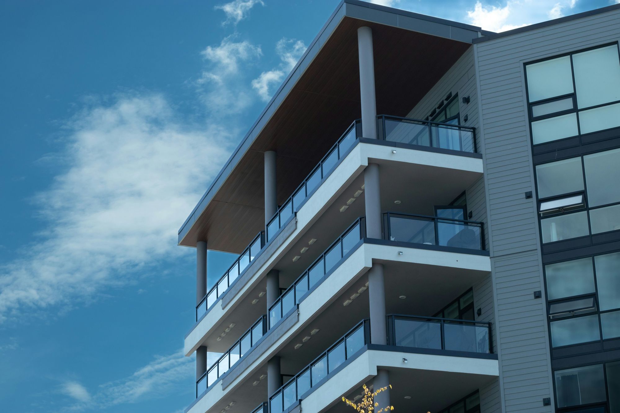 Modern condo building with glass-railed balconies against a blue sky
