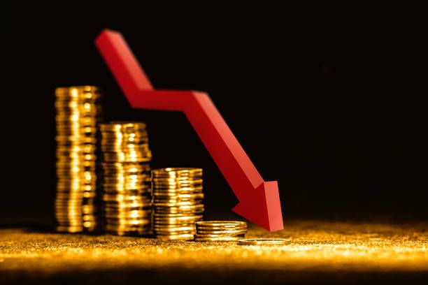 Stacks of gold coins shrinking beside a red downward arrow