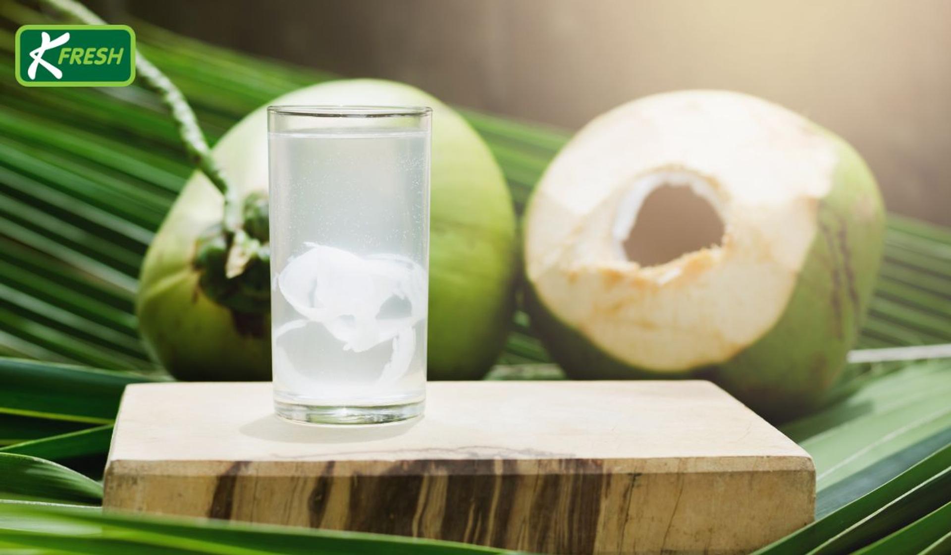 Coconut water in a glass placed next to a green coconut.