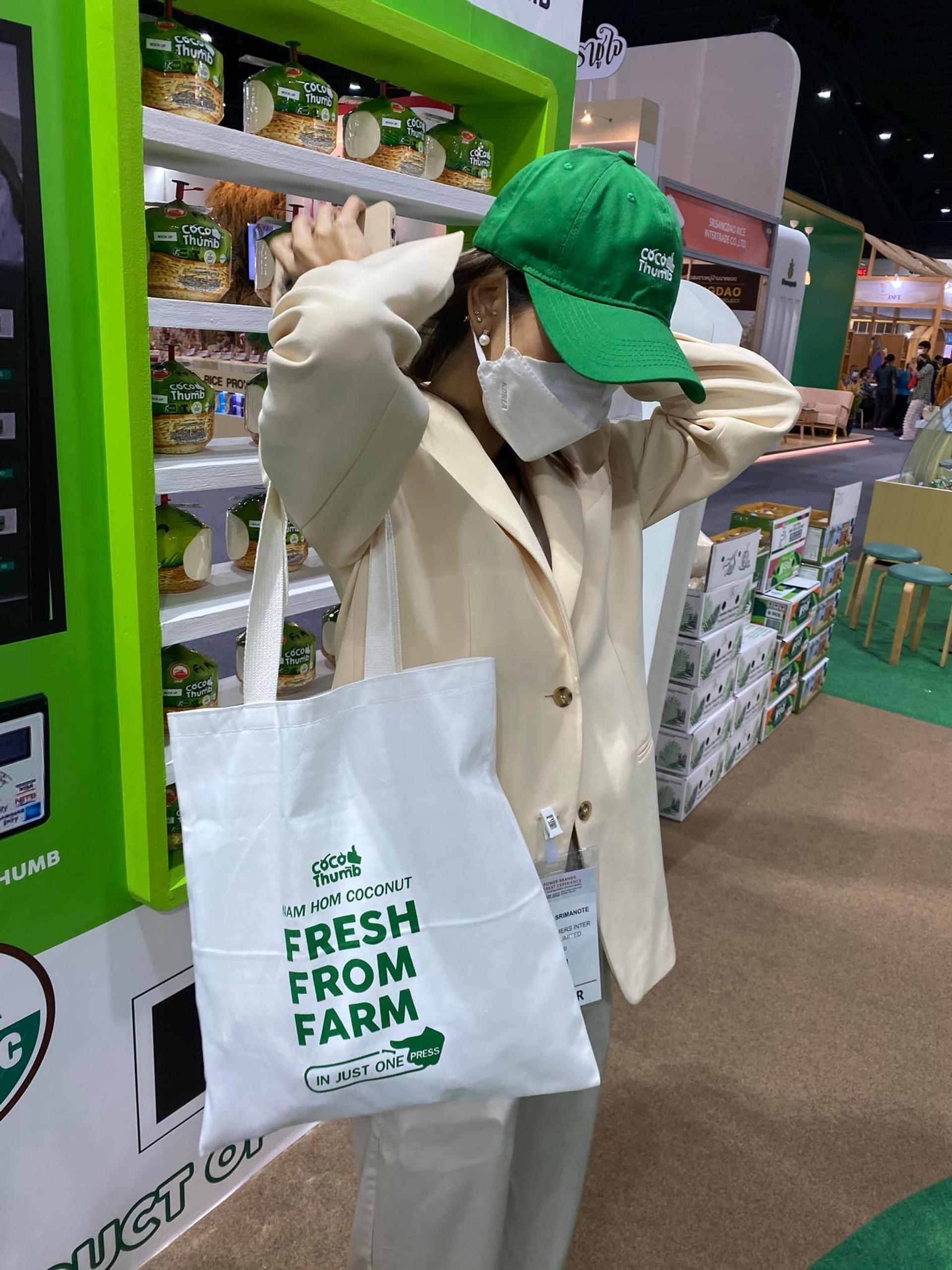 Visitors are wearing green hats and carrying K fresh cloth bags.