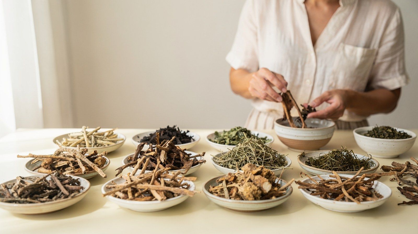 Radici ed erbe essiccate in piccole ciotole di ceramica.