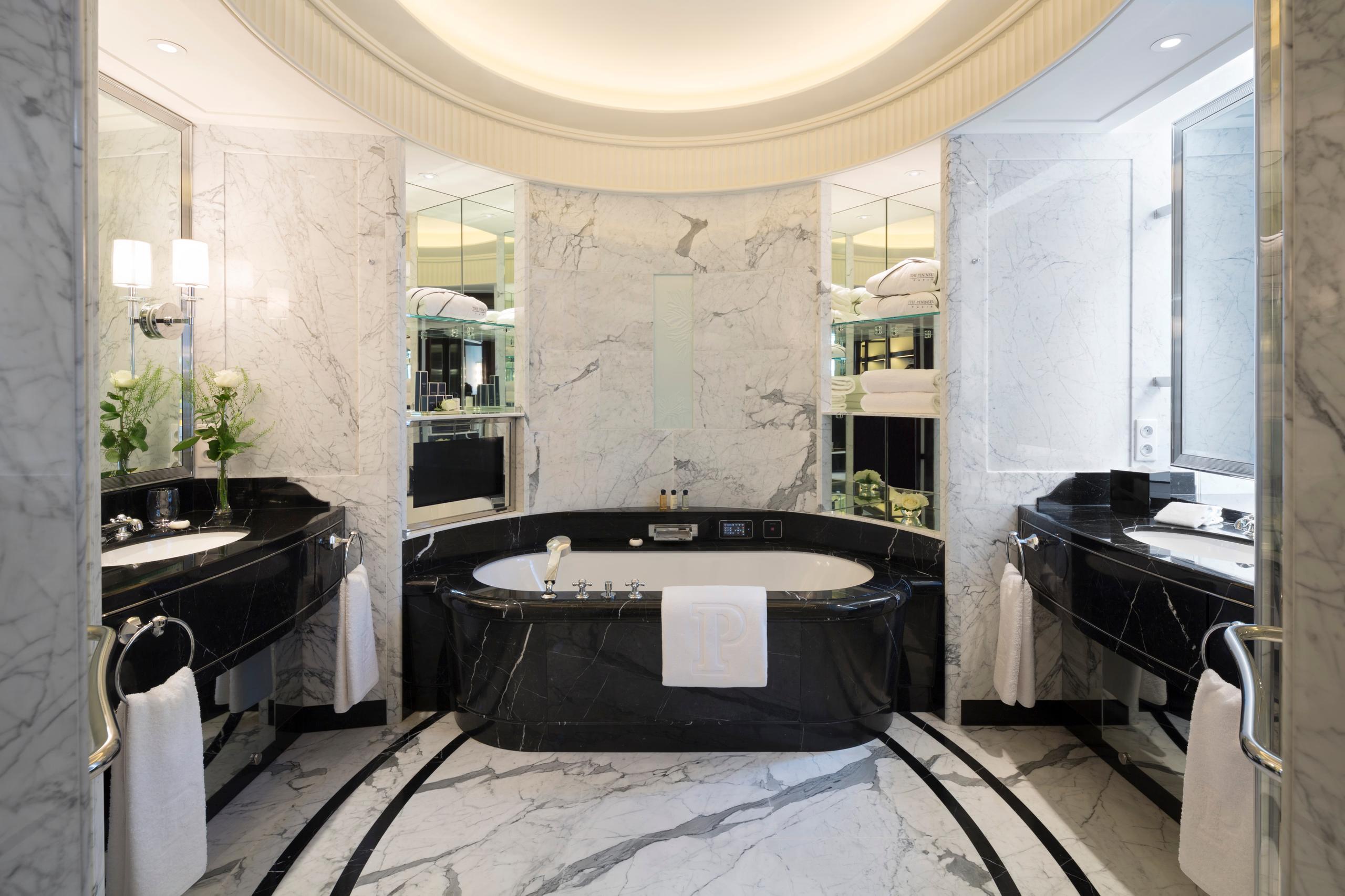 The Peninsula: bathroom with a black marble oval soaking tub centered under a curved ceiling with concealed lighting