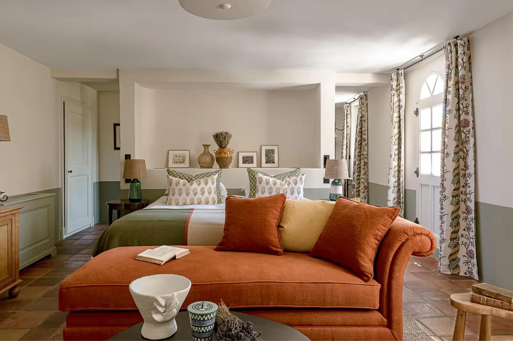Hôtel Crillon le Brave: a spacious room with pale green walls, a daybed lounge, patterned curtains, and bright windows overlooking countryside
