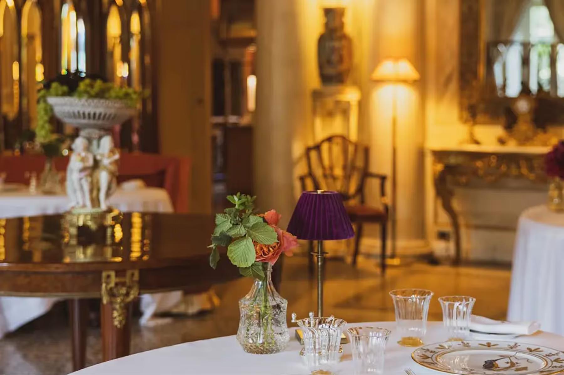 Passalacqua: an elegant interior dining room with cream walls, gilded mirrors, and soft lighting