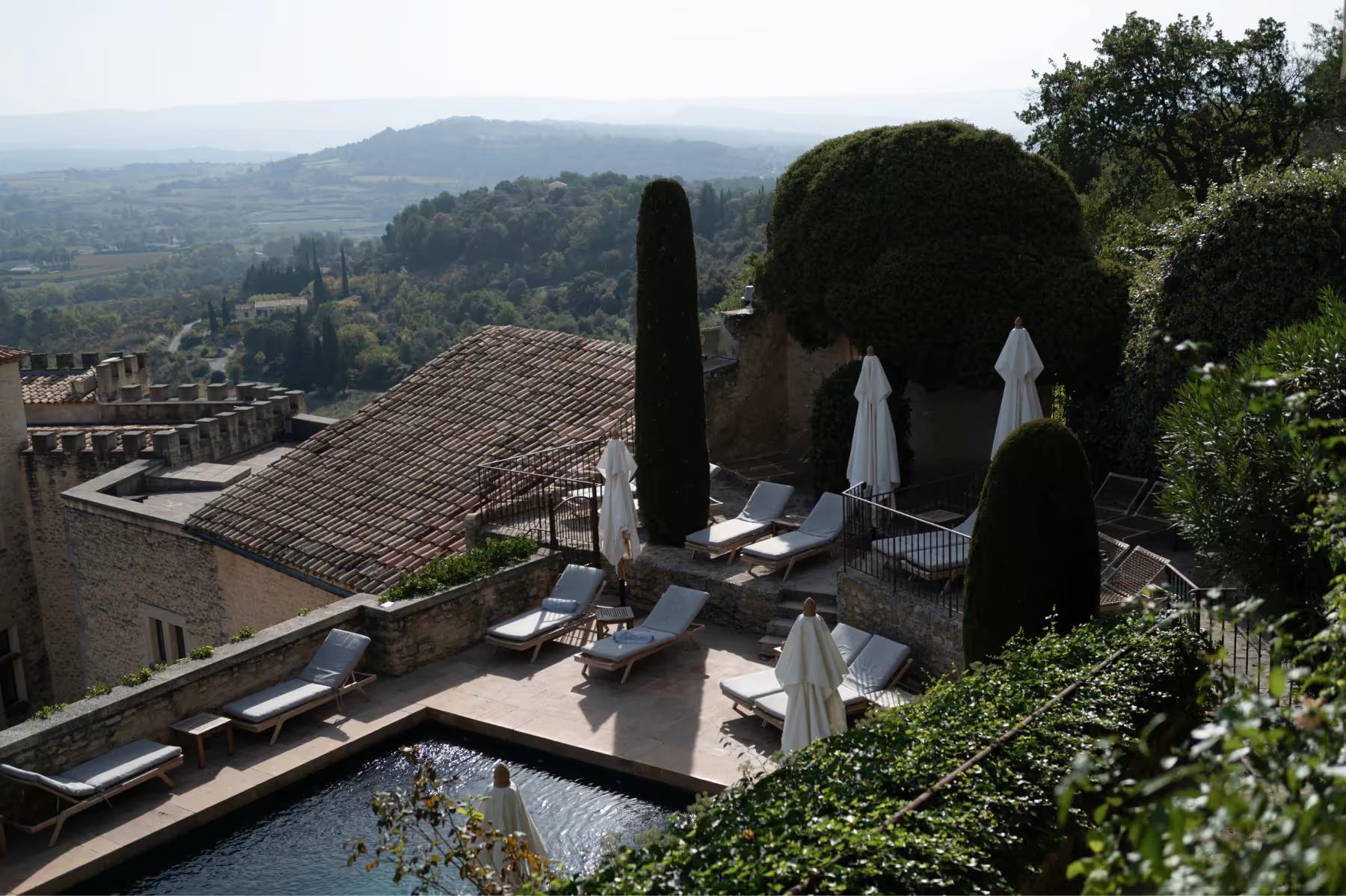 The pool terrace with cypress trees, umbrellas, and panoramic views of the Provençal countryside