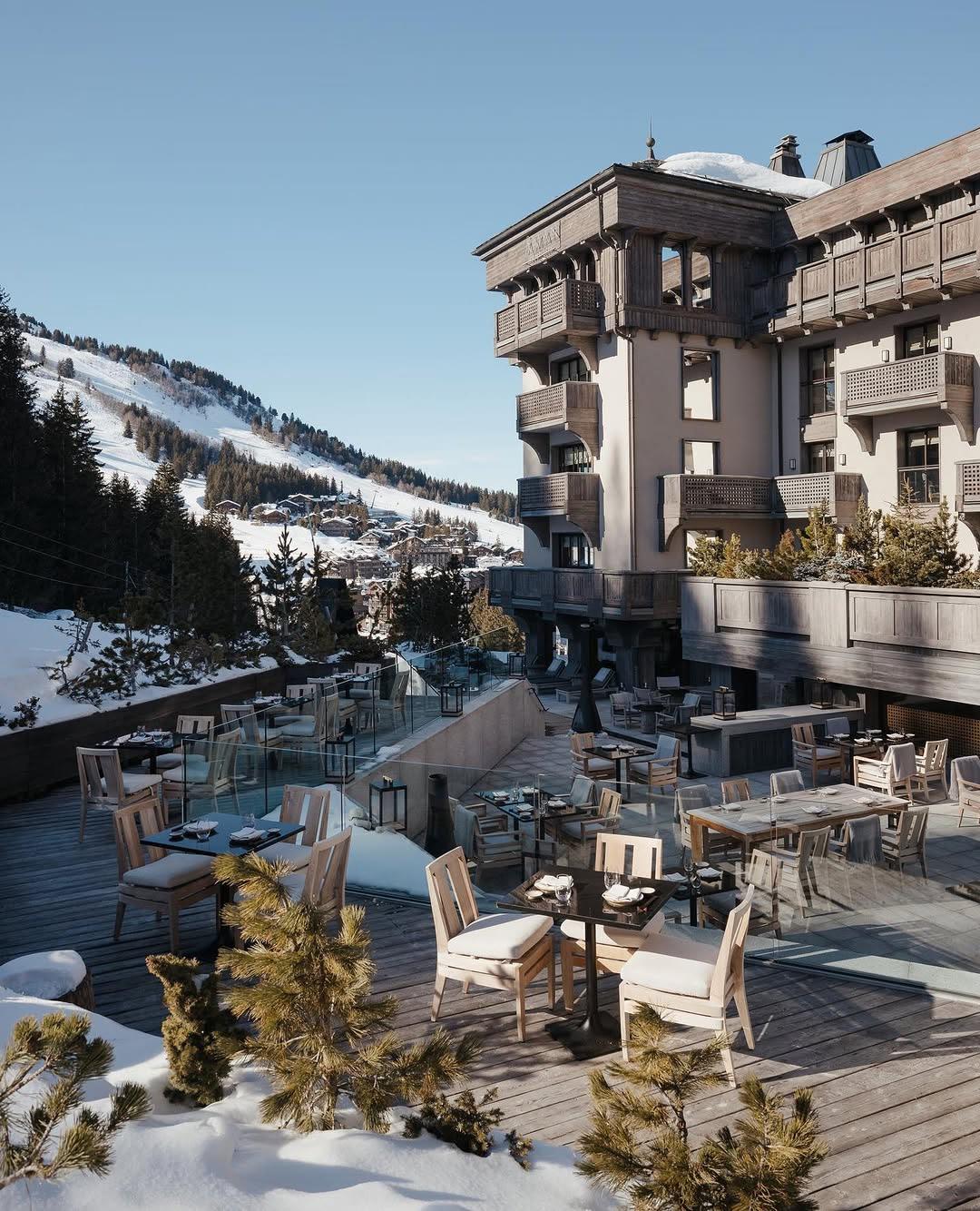 Aman Le Mélézin: chalet exterior and terrace dining deck overlooking the village, ski slopes, and mountains