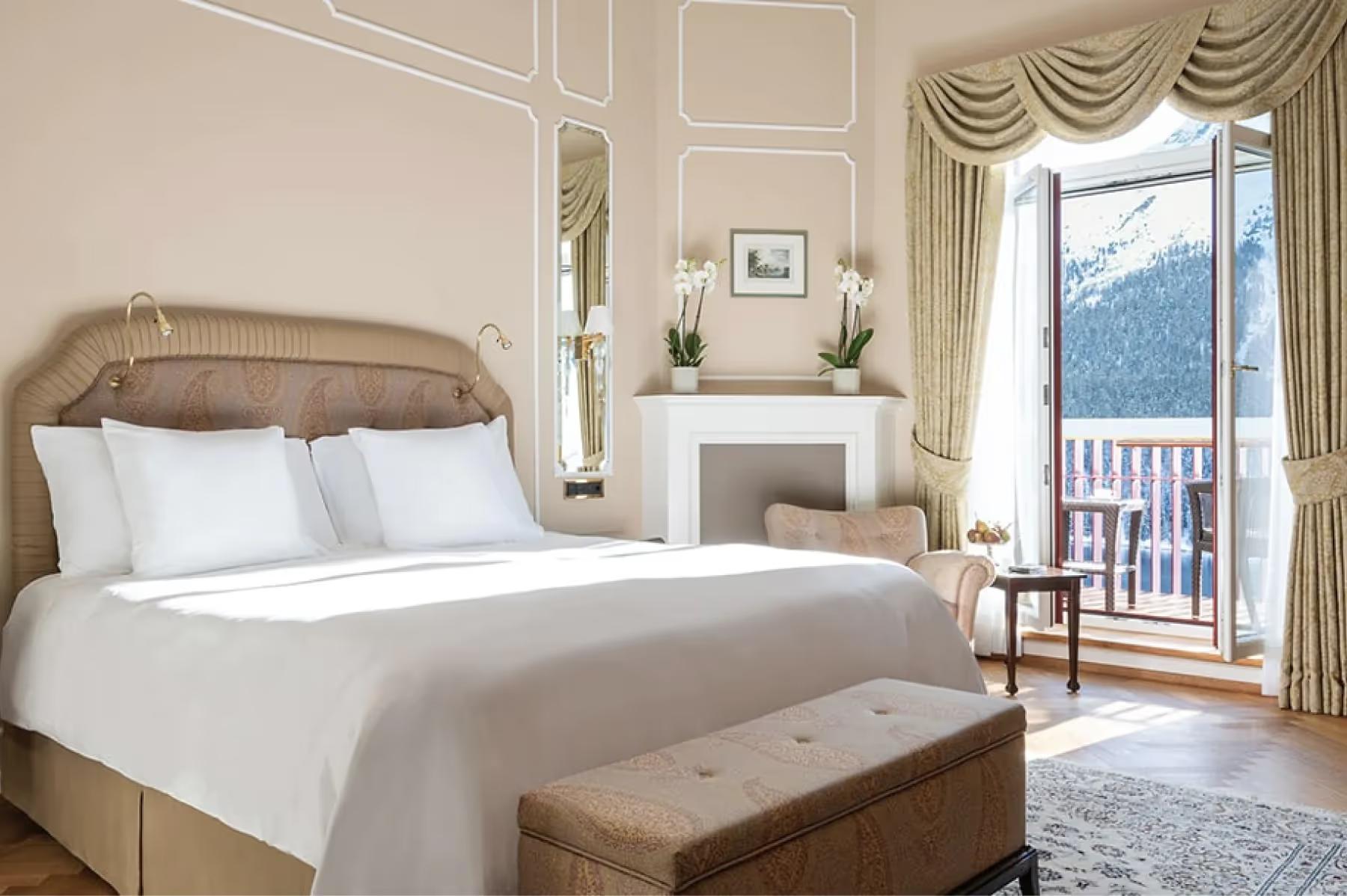 Badrutt’s Palace Hotel: bedroom with upholstered headboard, white linens, balcony with lake view