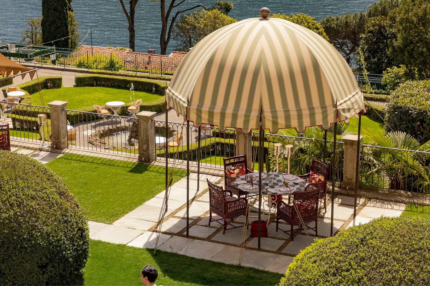 Passalacqua: a striped dome tent covers an outdoor dining setup surrounded by manicured hedges