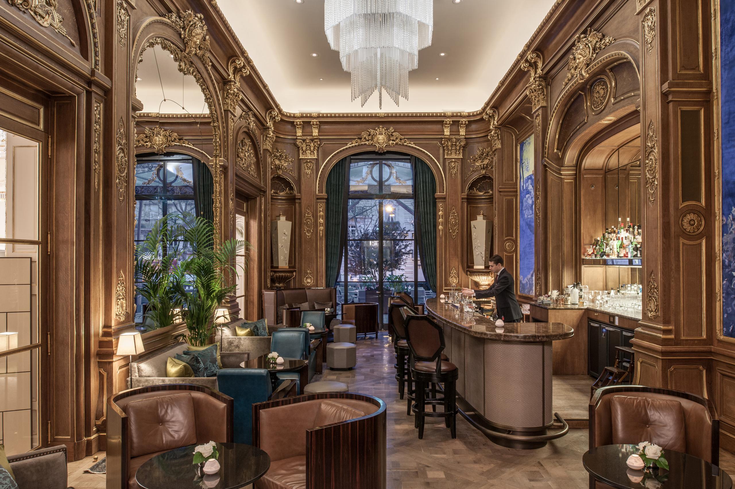 The Peninsula: ornate lounge with wood paneling, blue velvet seating, arched ceilings, and classical fixtures