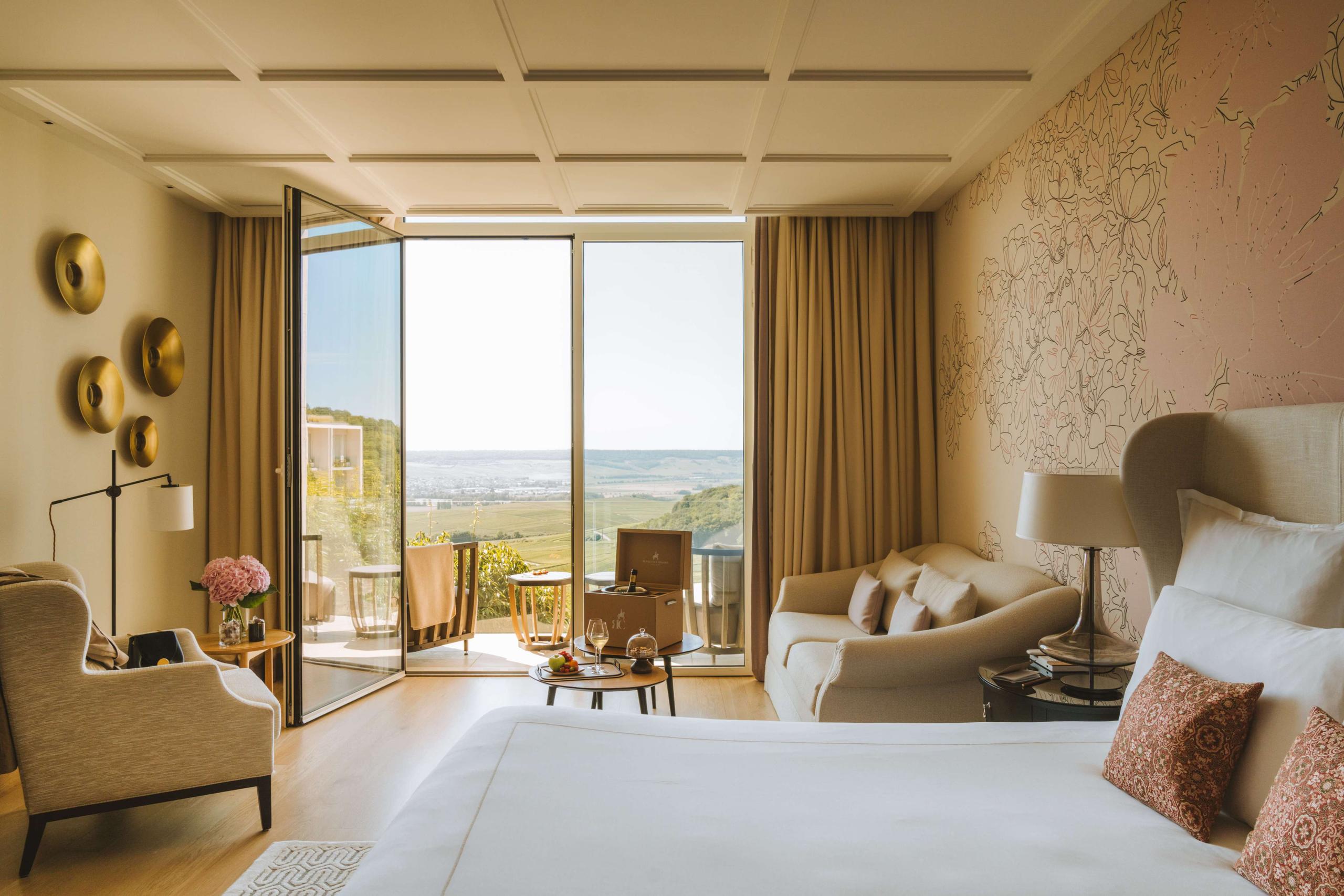 Royal Champagne Hotel & Spa: bedroom with large windows framing green vineyard landscape, gold curtains, and neutral furnishings