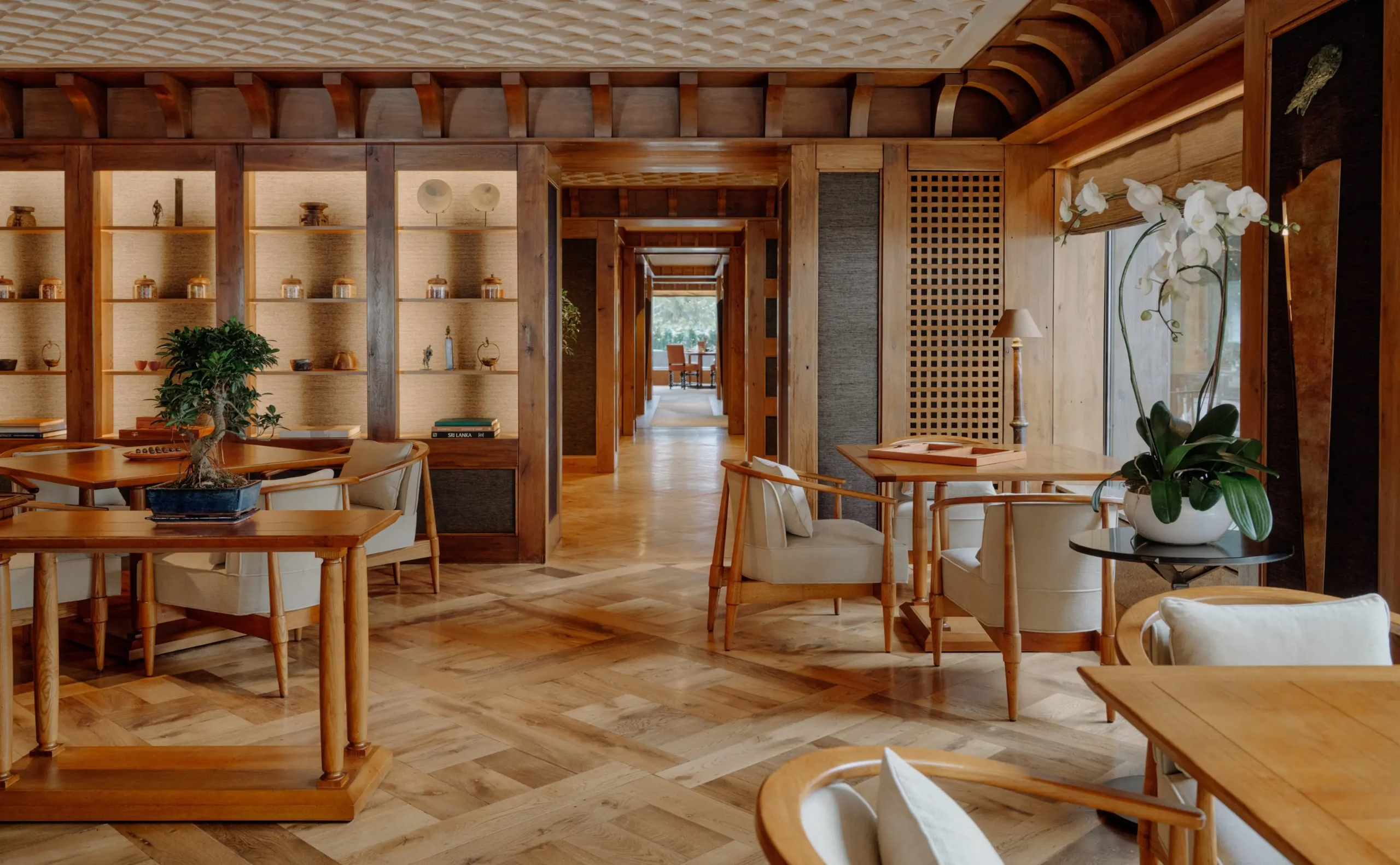 Aman Le Mélézin: Akari dining room with ceramic display shelving, bonsai, and tables set beneath a beamed ceiling