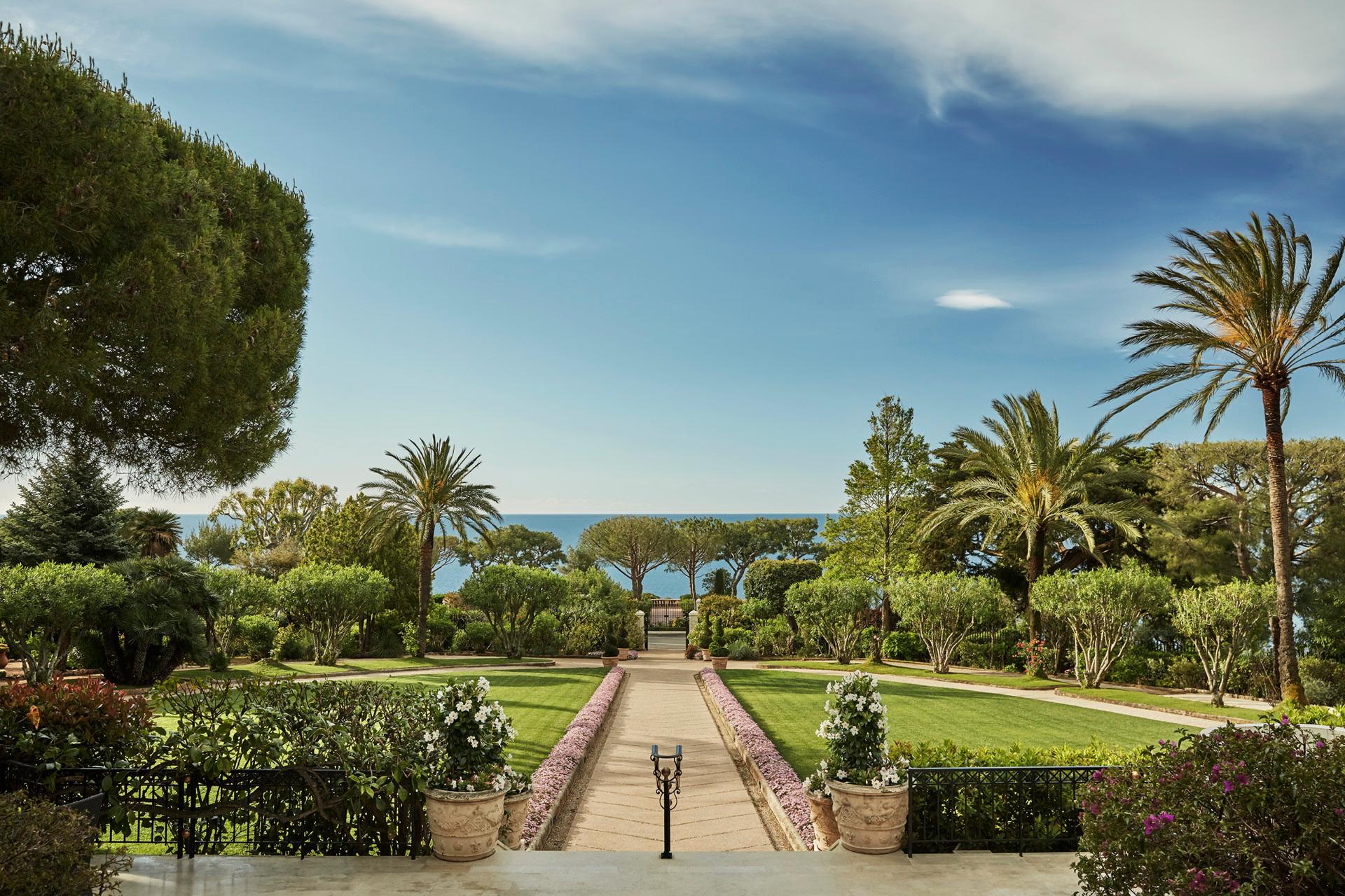 Palm trees and Mediterranean gardens with stone pathways and sea view