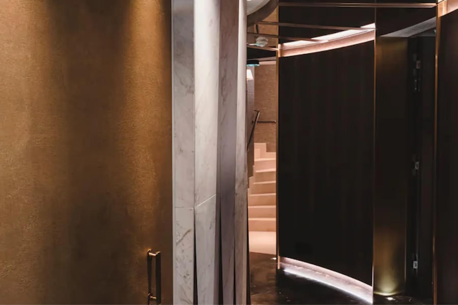 Maison Villeroy: a spa corridor with brass railings and dark walls
