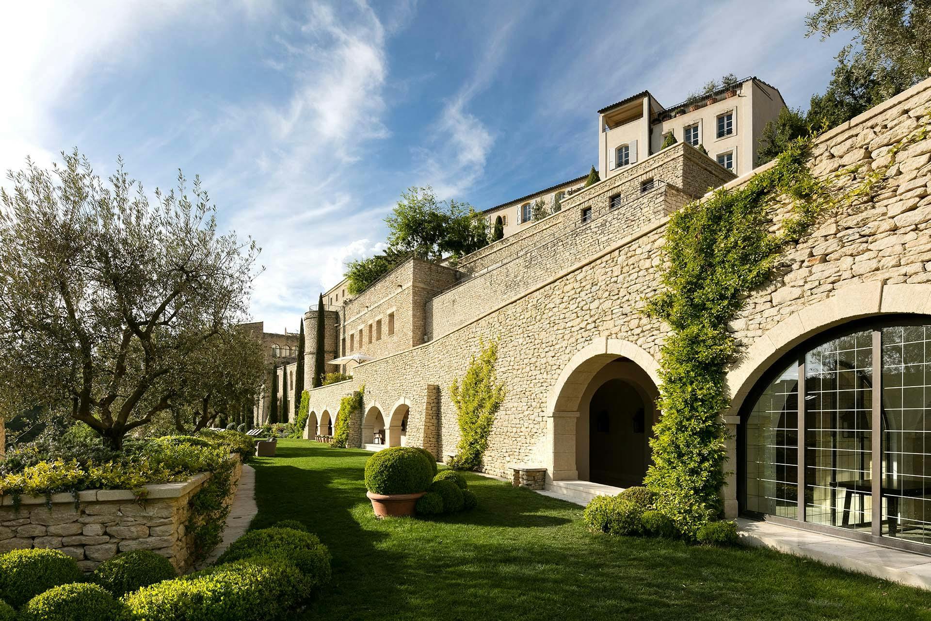 Stone archway opening to gardens with cypress and mountain vistas