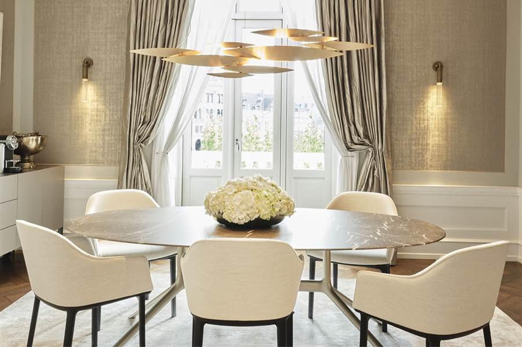 Dining room in cream tones with brass chandeliers and tall windows
