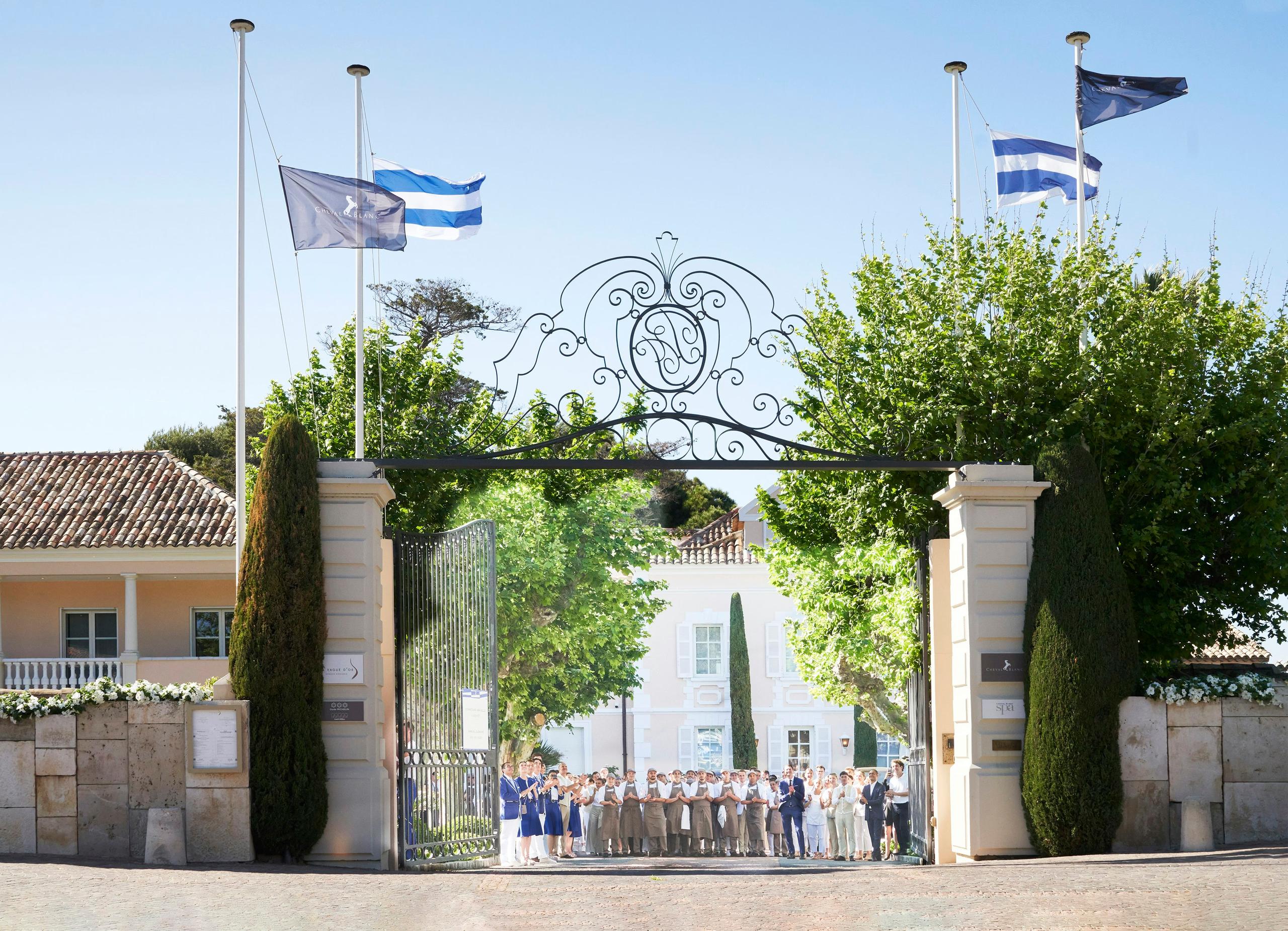 Ornate entrance gate with decorative sculpture and planted urns