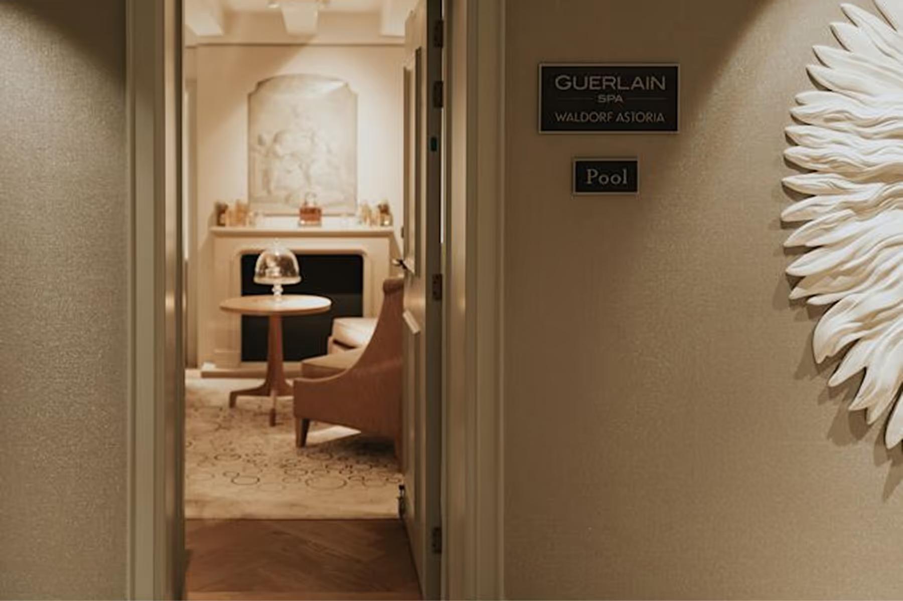 Waldorf Astoria Amsterdam: a treatment room entrance with a Guerlain spa sign, minimalist styling, and a white sculptural accent wall