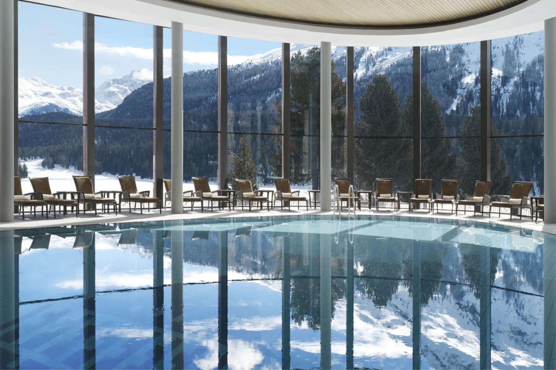 Badrutt’s Palace Hotel: indoor infinity pool with floor-to-ceiling windows framing mountain landscape