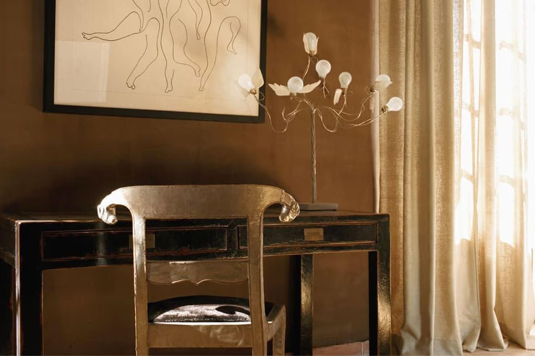 Le Mas de Chabran: dressing table with curved mirror, white flowers in vase, and framed line drawing
