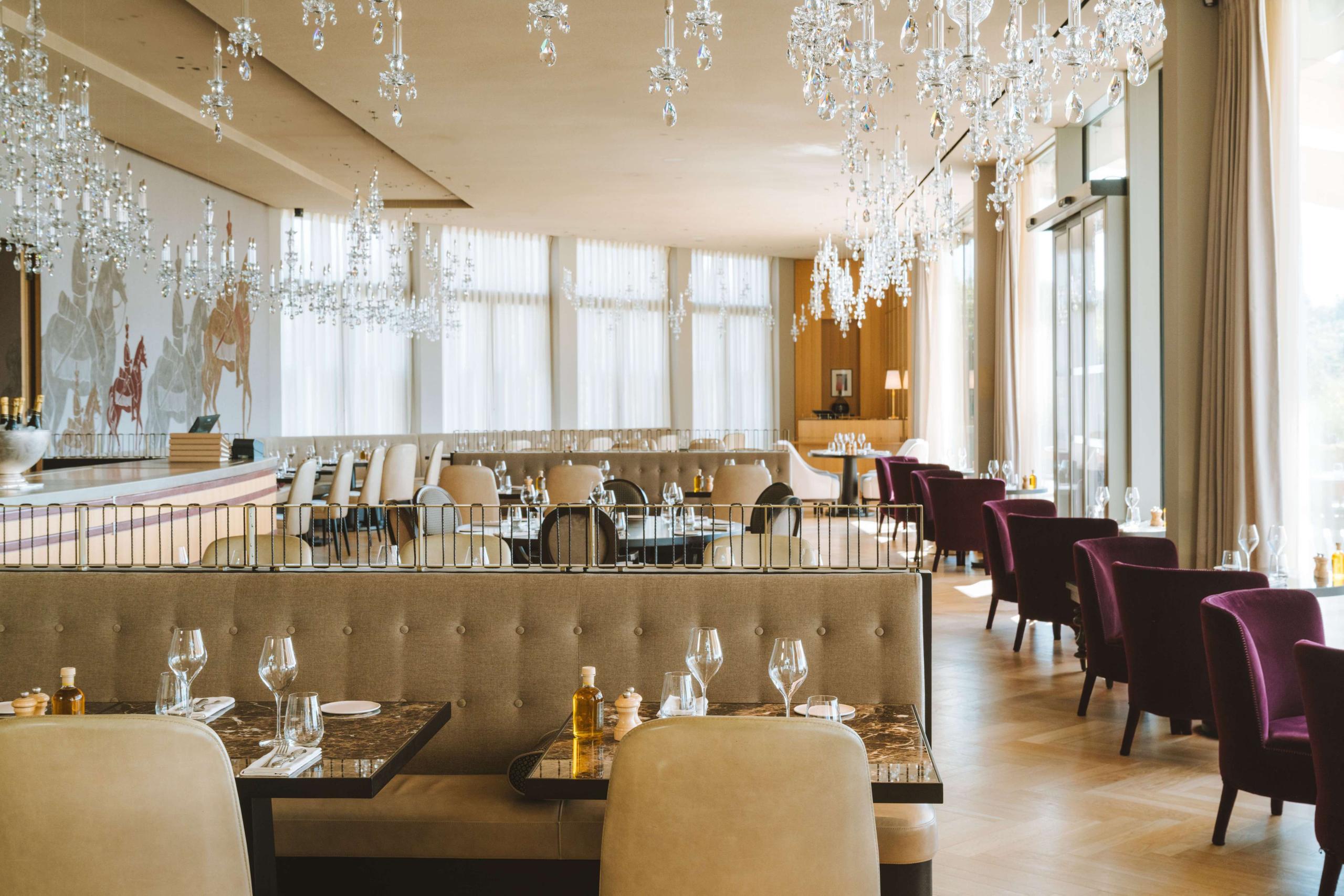 Royal Champagne Hotel & Spa: fine dining room with crystal chandelier, gold ceiling details, and long banquettes in wine tones